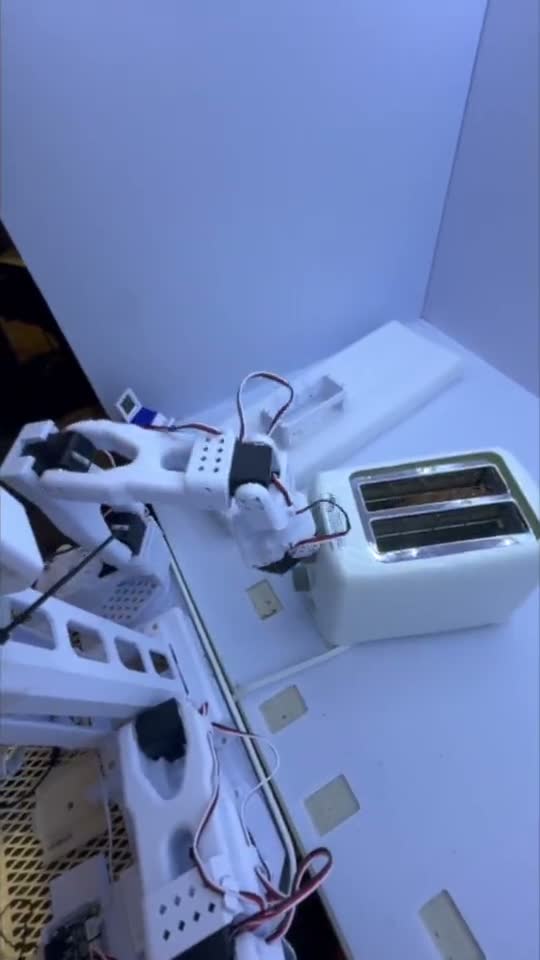 A robot arm placing bread into a toaster