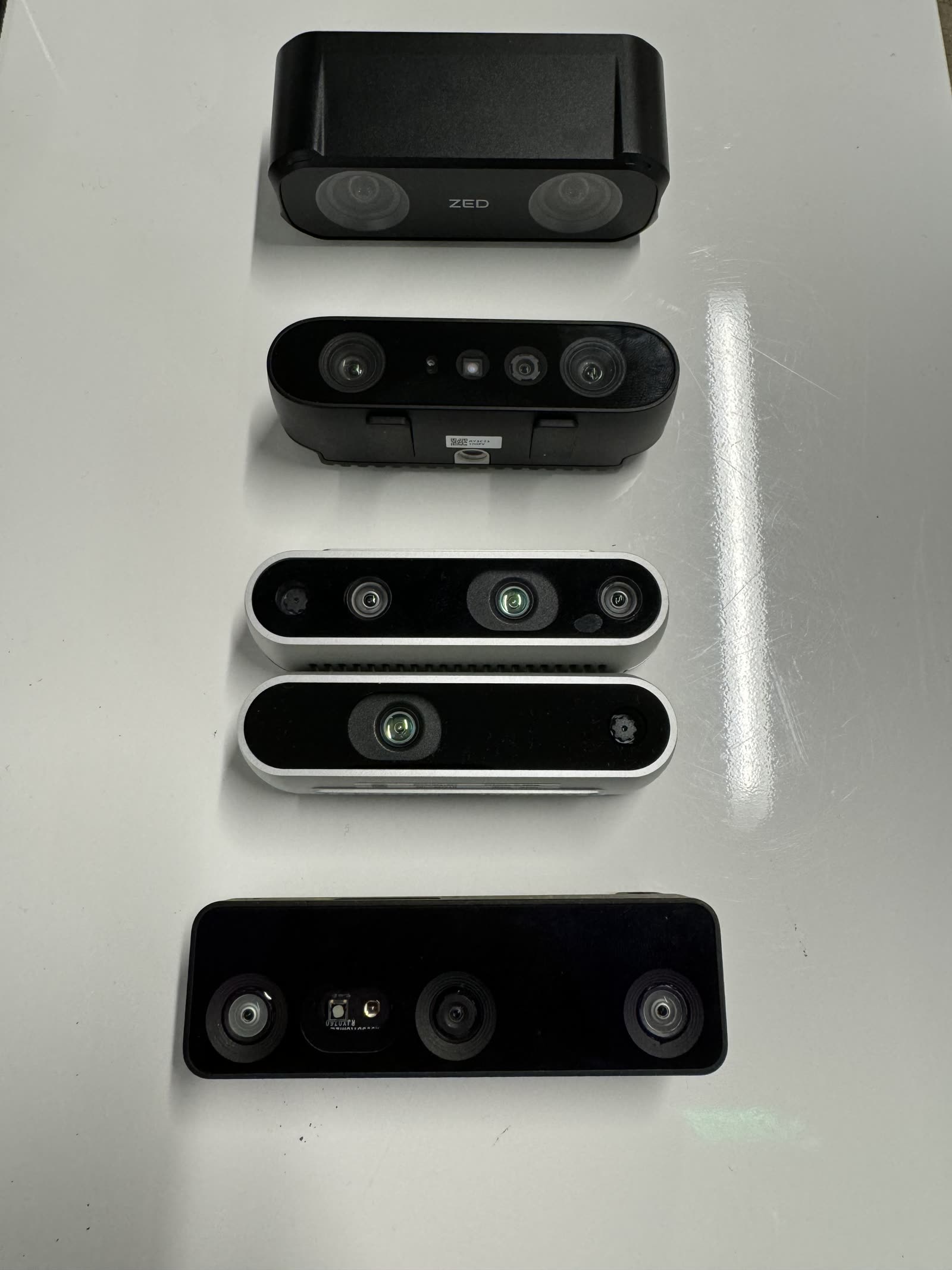 Four of the depth cameras evaluated: ZED, Luxonis, RealSense, Orbbec, laid out side by side